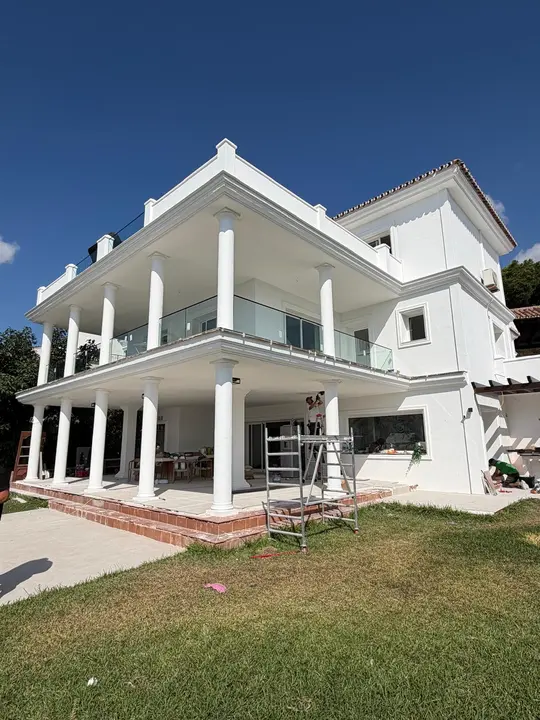 Barandillas de cristal en los balcones de una villa con columnas