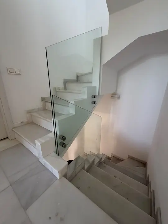 Barandilla de cristal en escalera blanca de mármol