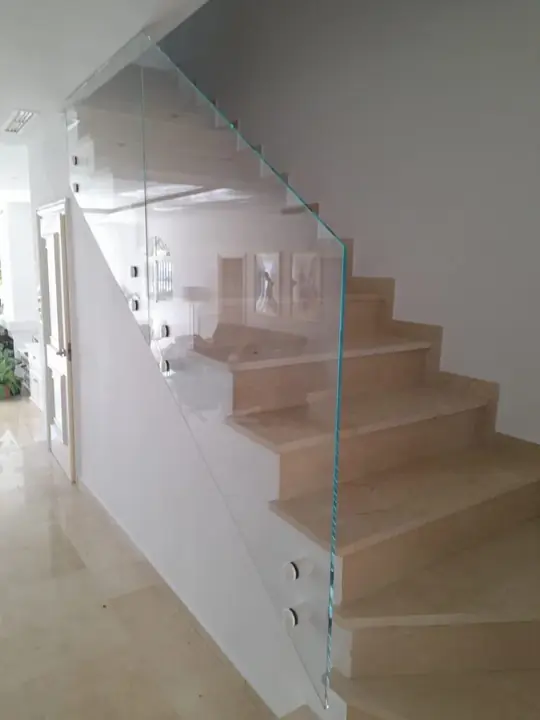 Barandilla de cristal con pinzas en escalera de mármol