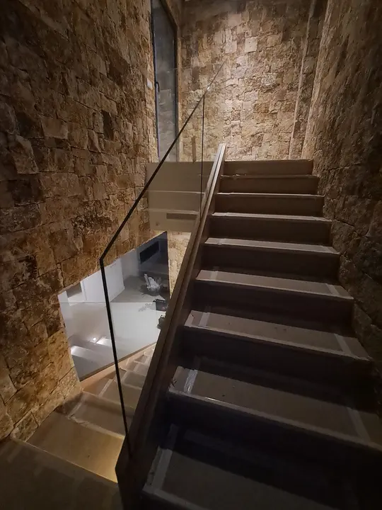 Barandilla de cristal en escalera con muro de piedra