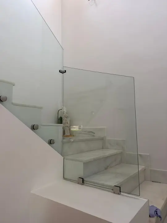 Barandilla de cristal con pinzas en rellano de escalera