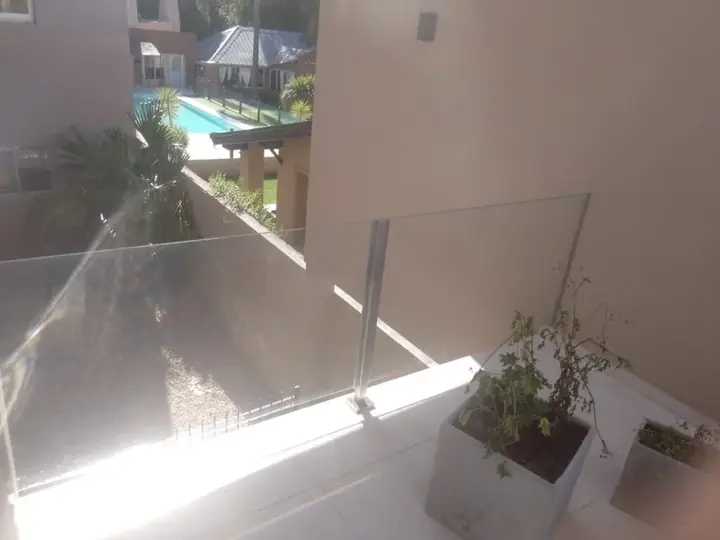 Barandilla de cristal en terraza con jardín y piscina