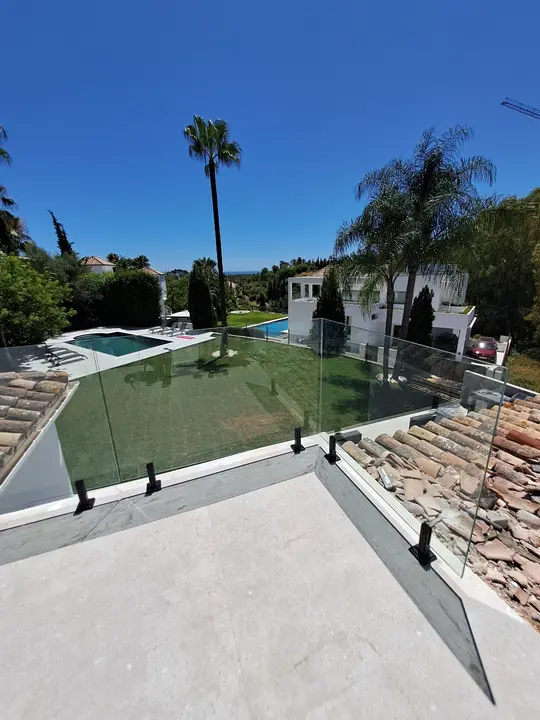 Barandilla de cristal con pinzas en terraza con piscina