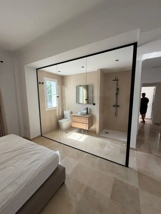 Cerramiento de cristal de suelo a techo entre dormitorio y baño