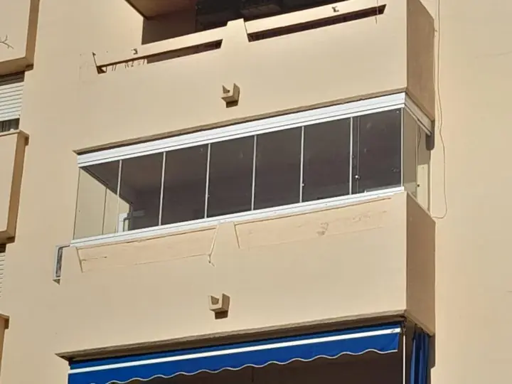 Fachada con balcón acristalado mediante cortina de cristal