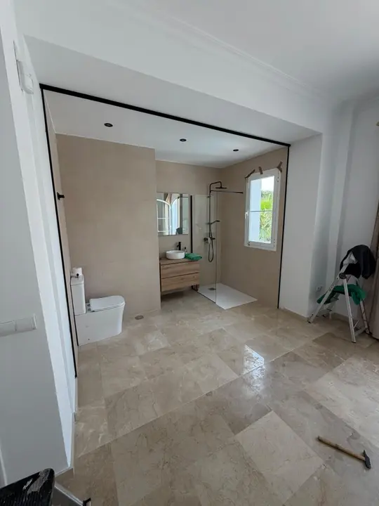 División de cristal con perfilería negra en baño de suite