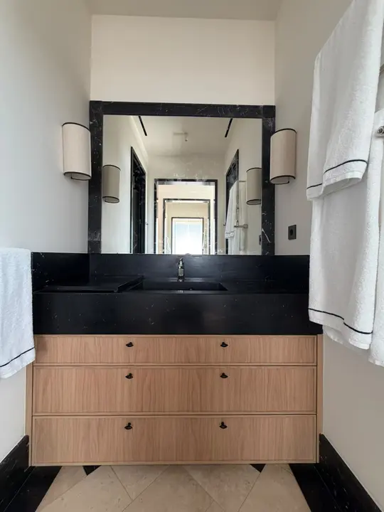 Espejo con marco negro y apliques en baño de mármol negro