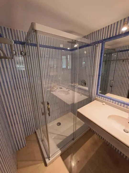 Mampara angular de cristal en baño con azulejo de rayas