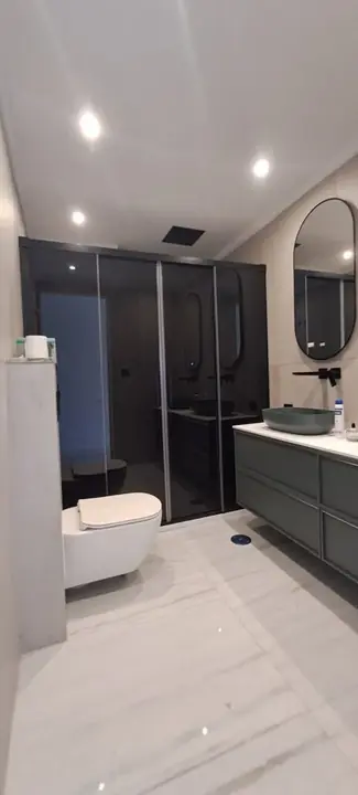 Mampara de ducha en baño moderno con espejo redondo