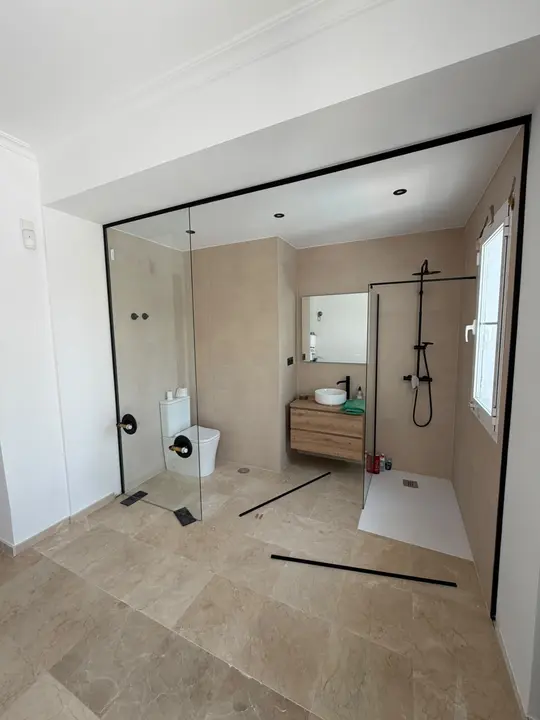 Mampara de ducha con perfil negro en baño de suite